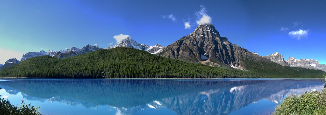 a large body of water with a mountain in the background, by Normand Baker, flickr, banff national park, symmetry!! water, photoreal”, gigantic mountains