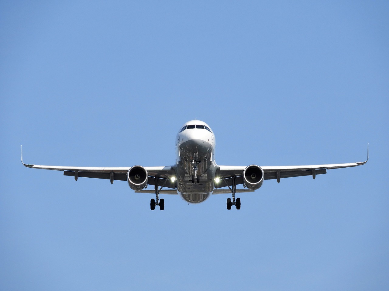 a large jetliner flying through a blue sky, a picture, by Jay Hambidge, pixabay, nose, landing lights, very clear picture, view from ground