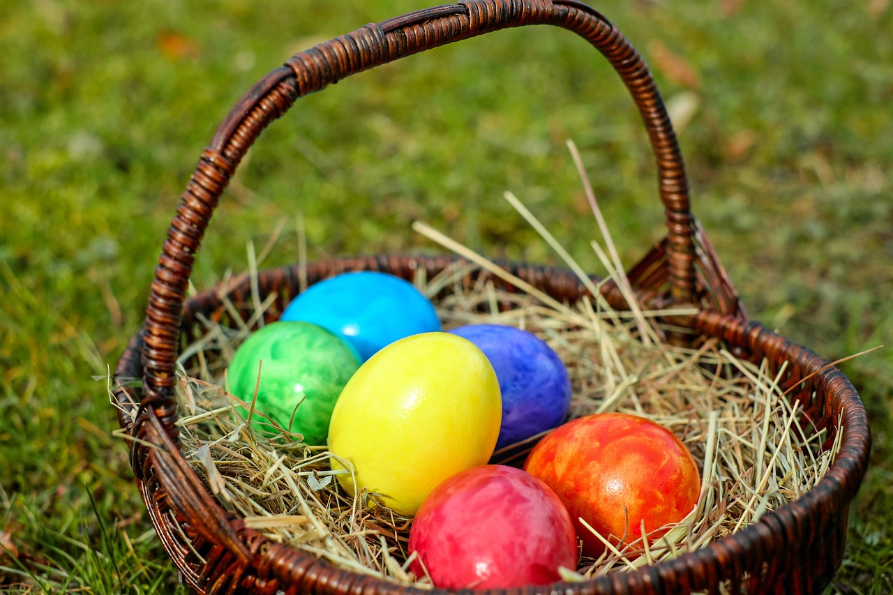 a basket filled with eggs sitting on top of a grass covered field, bright vivid colours, glazed, festive colors, seven