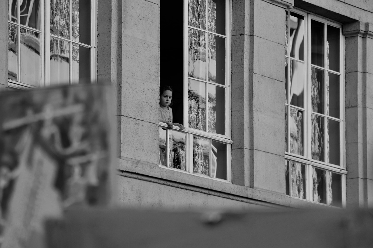 a man looks out his window of an apartment building