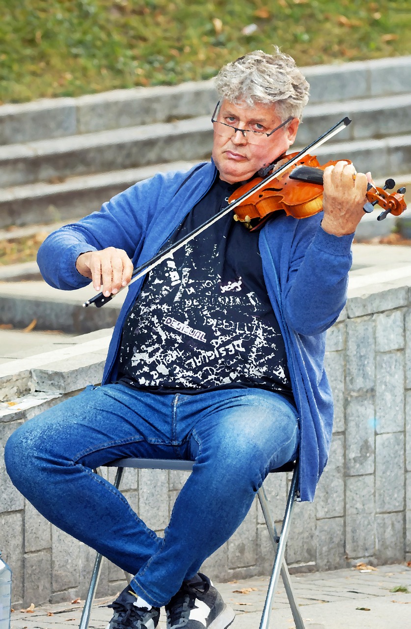 an older man playing violin on the sidewalk