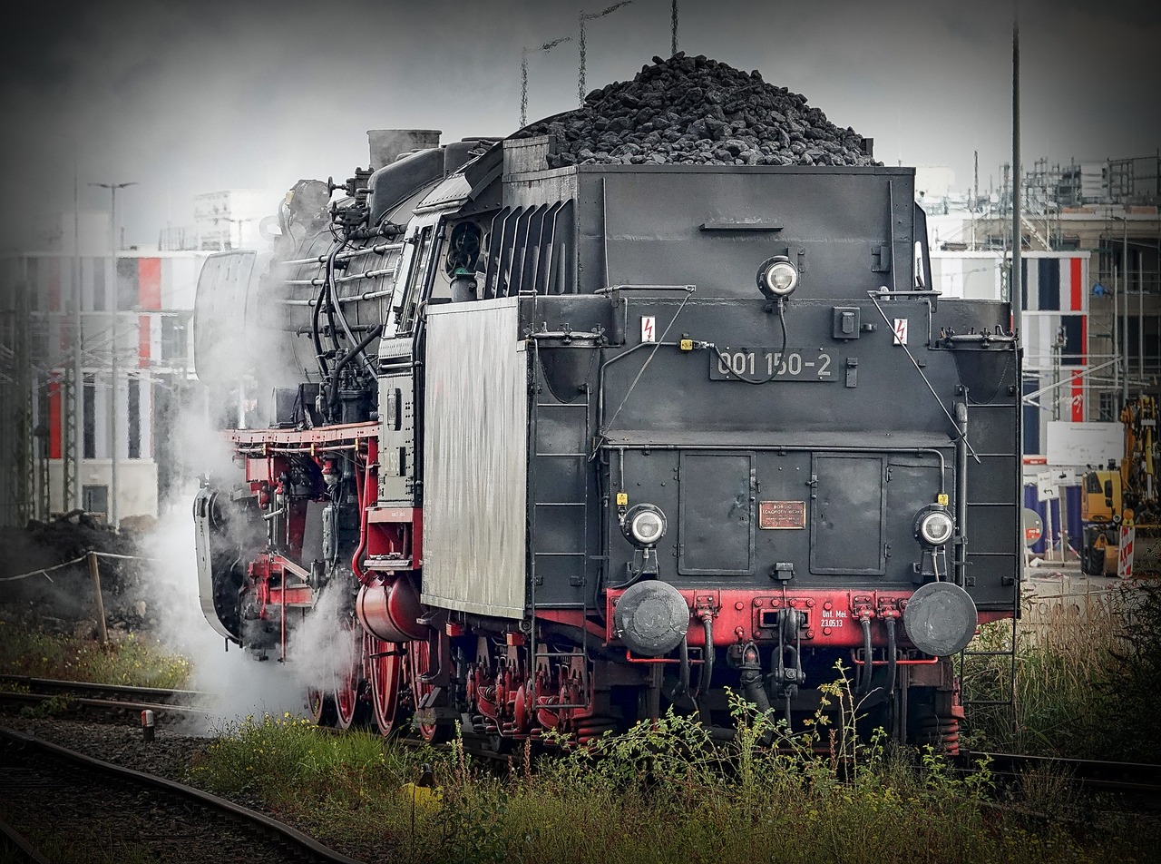 a large black locomotive parked near a pile of wood