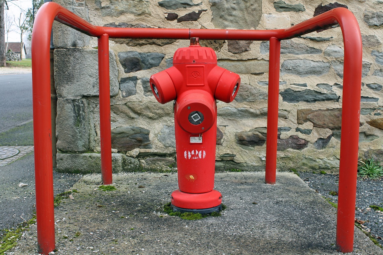 there is a red fire hydrant in front of a stone wall