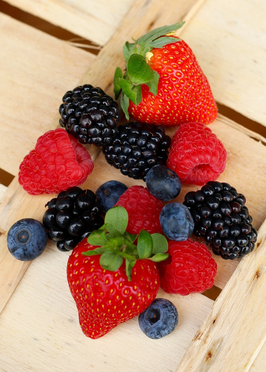 berries, strawberries, blueberries and raspberries on top of a wooden crate