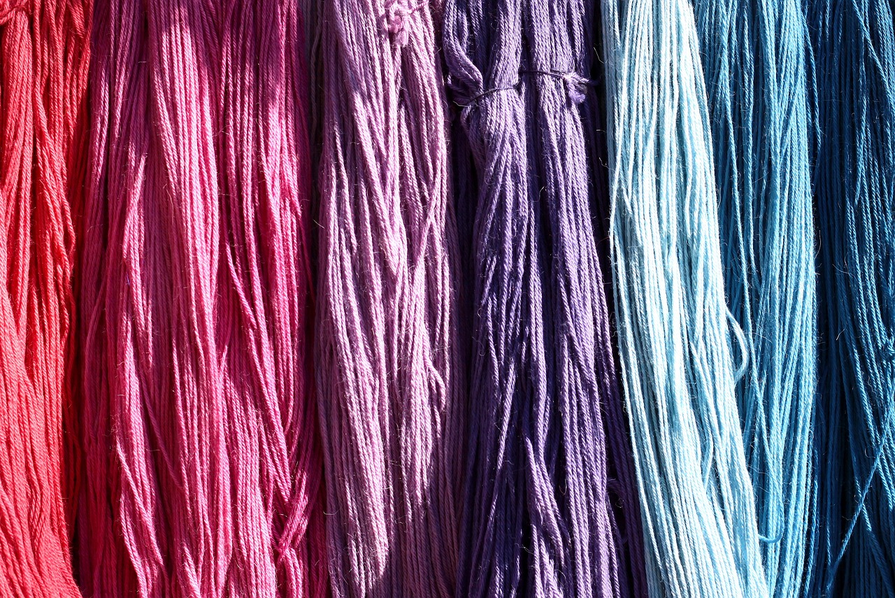 many colors of yarn hanging from a wooden hook