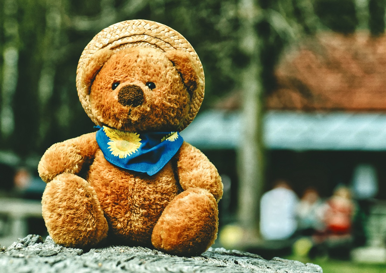 a teddy bear wearing a blue scarf sitting on a rock