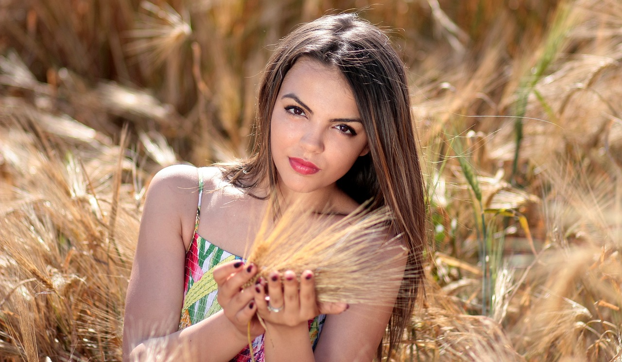 a woman in dress is standing with her hands behind wheat