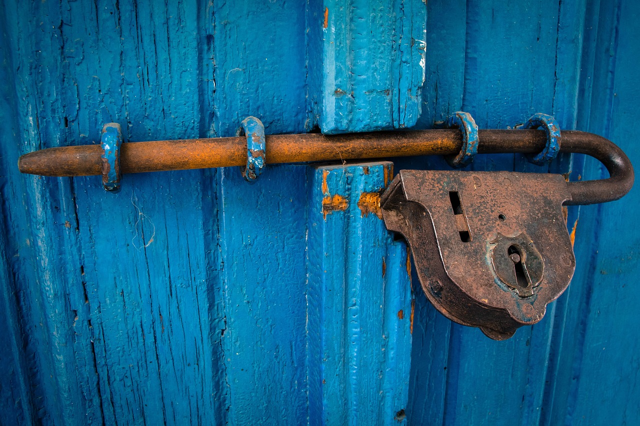 an old rusted lock on a blue door with a rusted handle