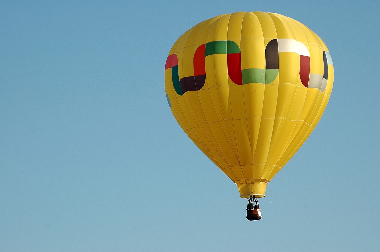 a bright yellow  air balloon is flying high in the sky