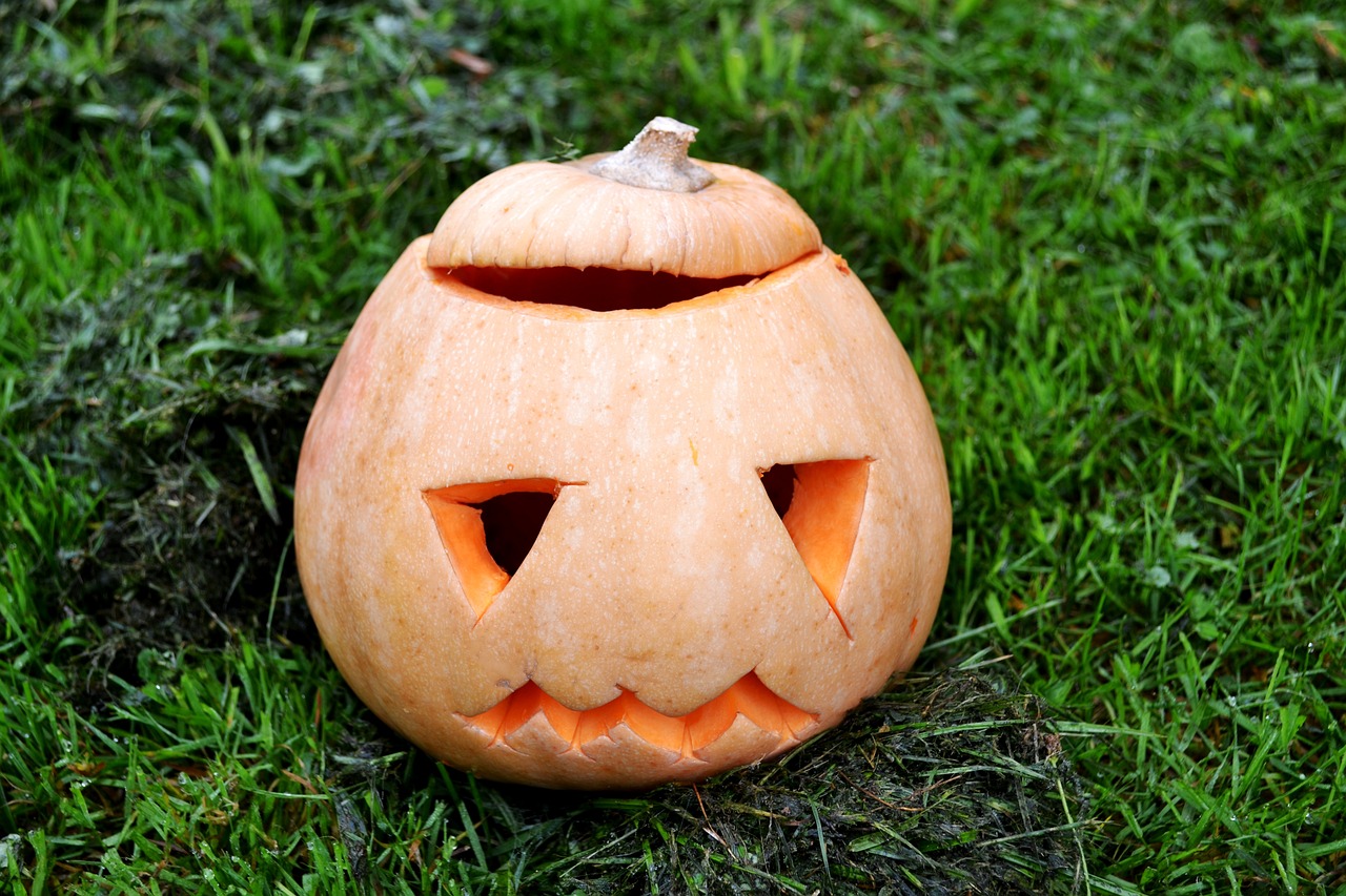 an carved pumpkin on the grass with two eyes
