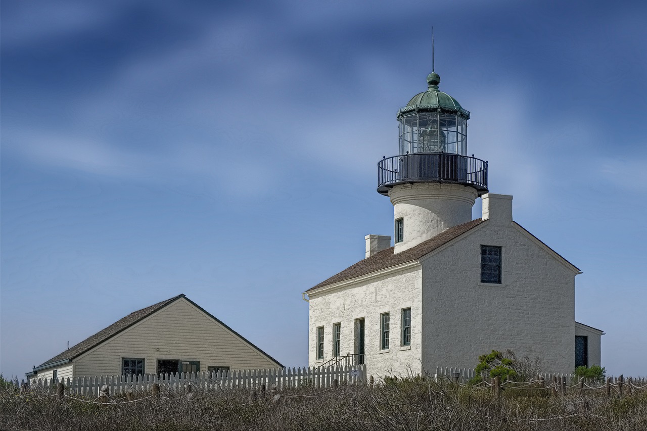 an old light house with two small towers and a fence surrounding it