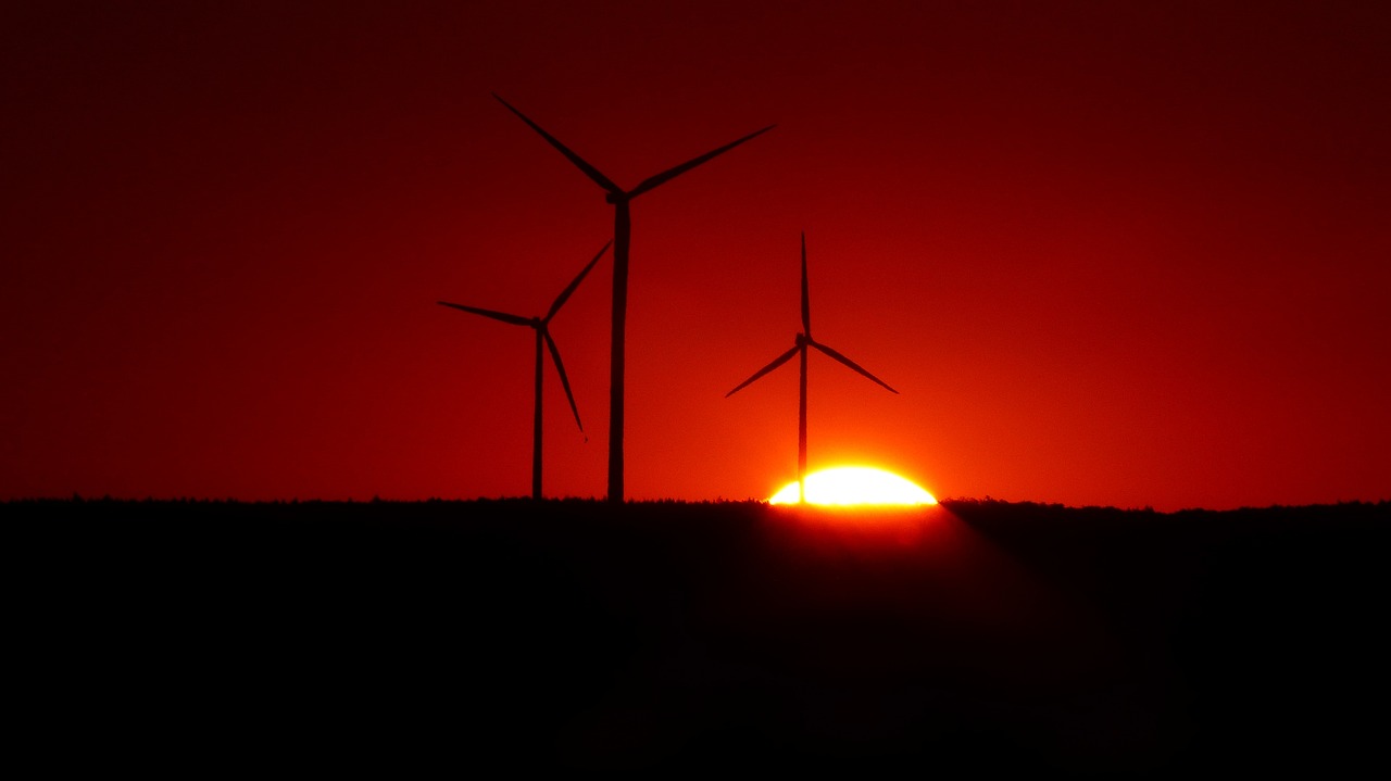 some windmills standing in a field with the sun behind them