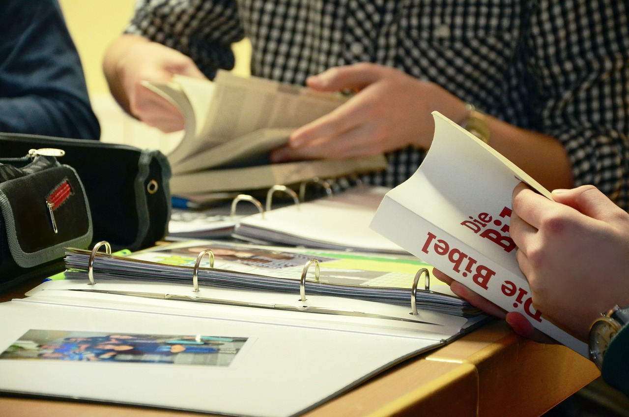 people working together at a table reading and holding books