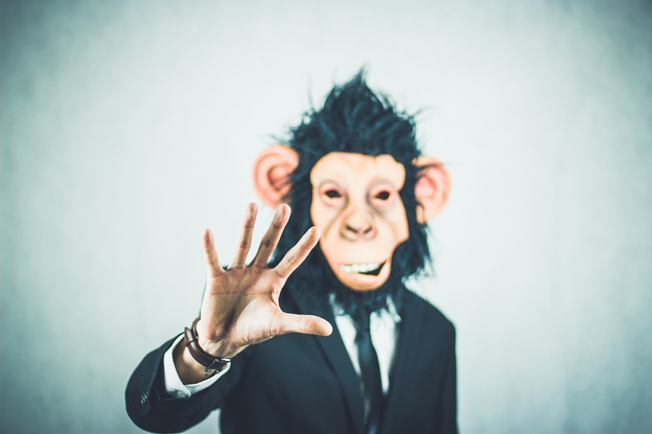 monkey face wearing suit and tie, and waving his hands with two fingers