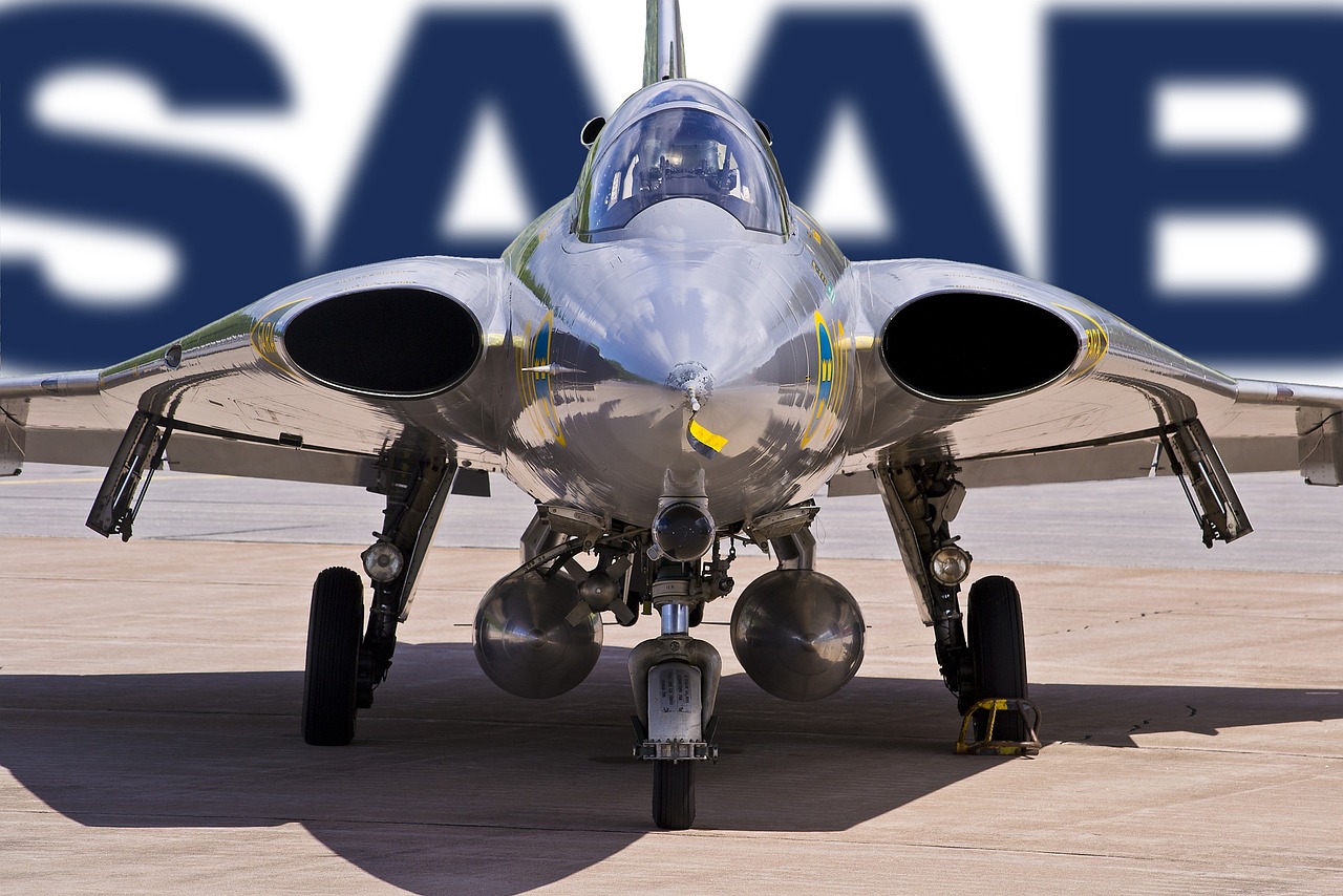 a silver fighter plane on a runway next to the sas sign