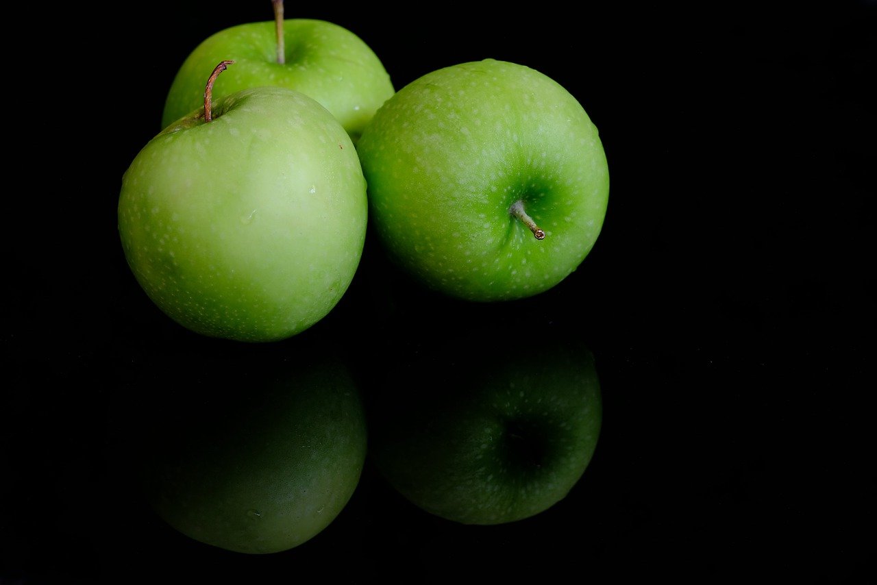 three green apples are sitting on top of each other