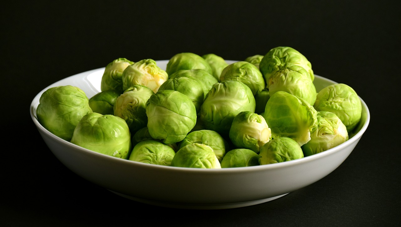 the bowl of green brussel sprouts on a black background