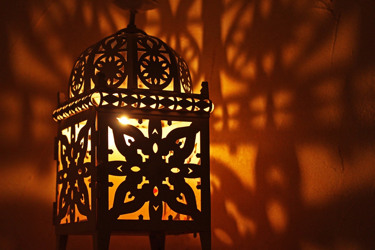 an ornate, bird - caged light shines brightly through the shadow of its owner