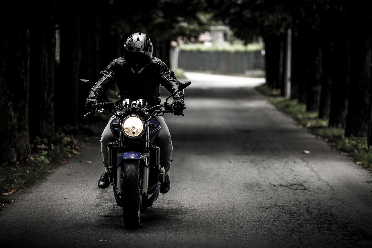 a man rides his motorcycle down a wooded road