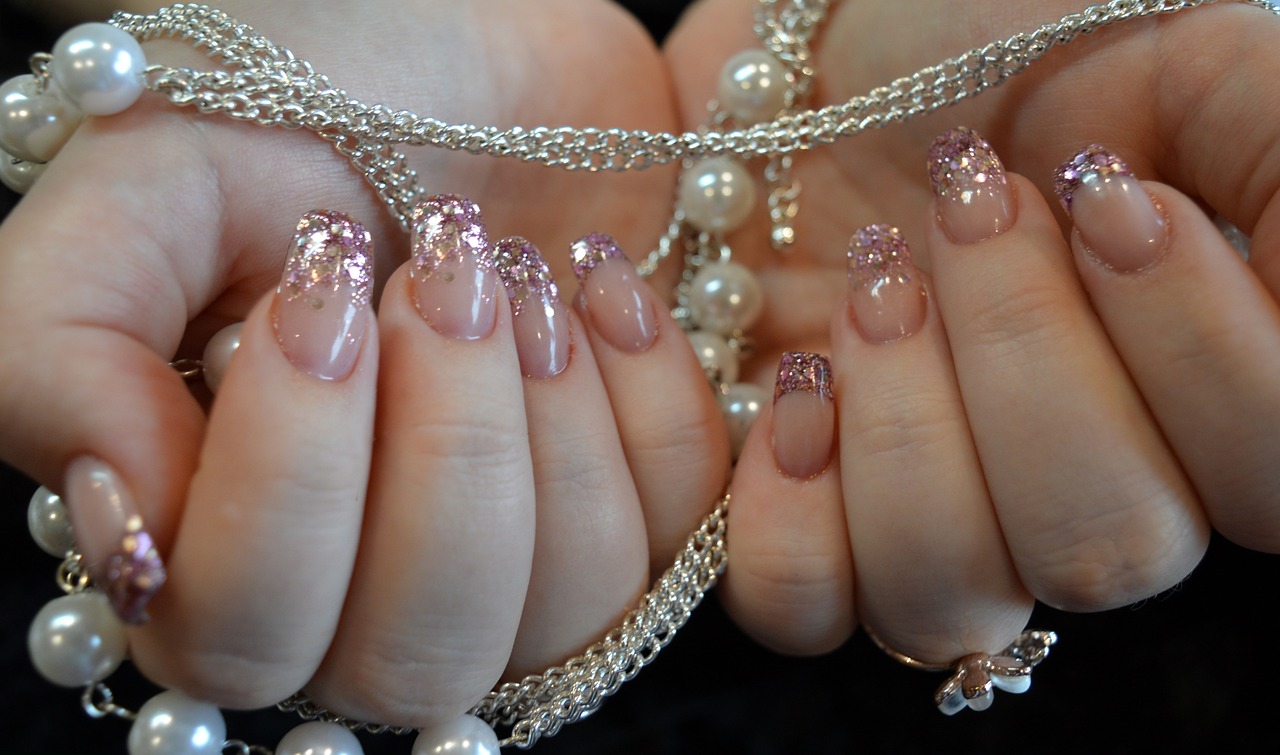 someone with pink and silver manicures holding a beaded chain