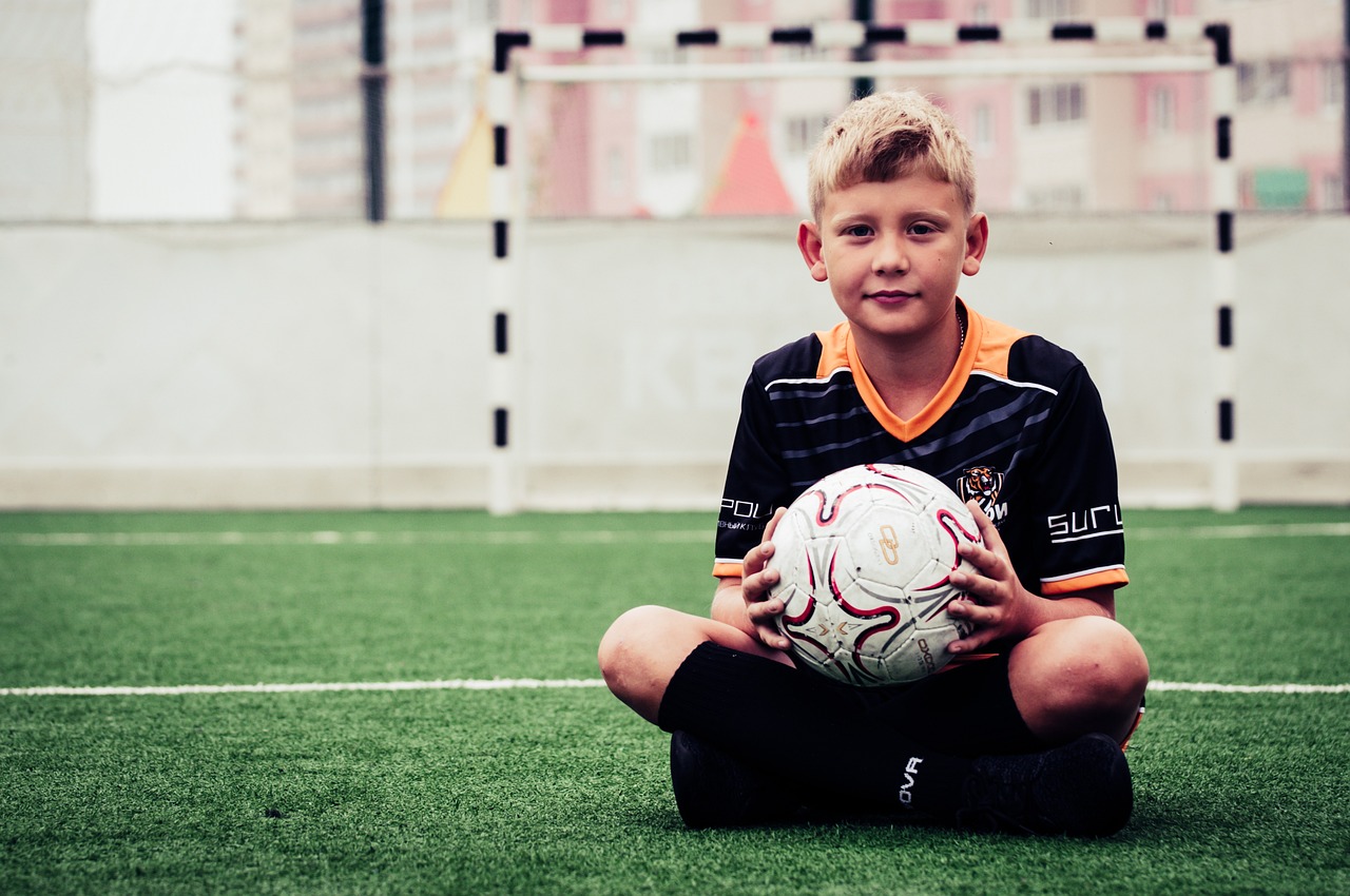 a boy is holding a soccer ball on the grass