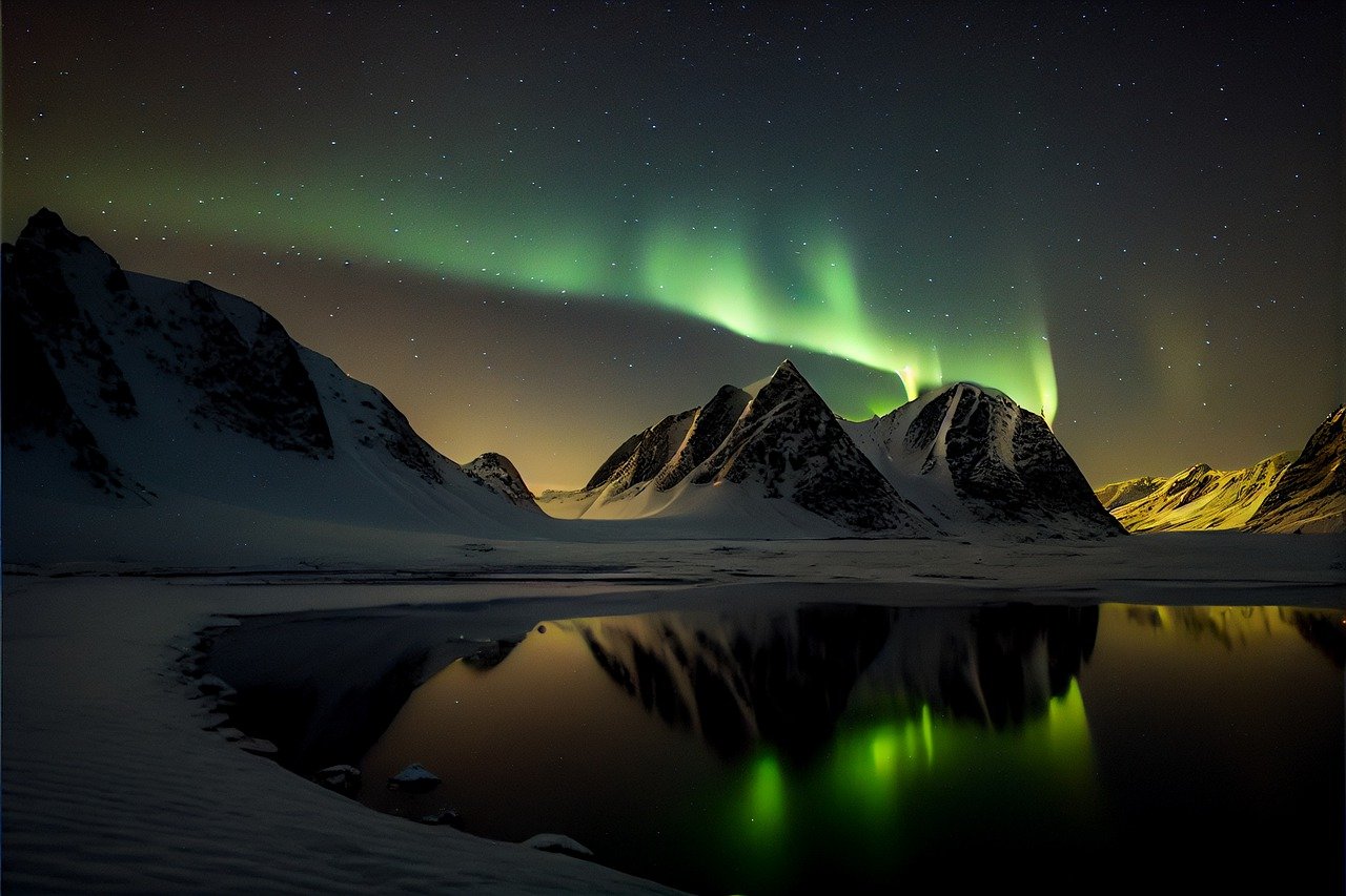 an aurora glow over a mountain and lake in the night