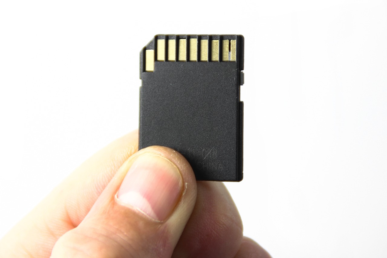 a small memory card being held up with a thumb