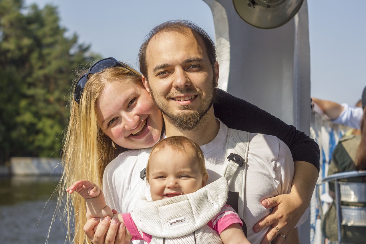 a man holding a woman who is wearing a baby strapped to her back