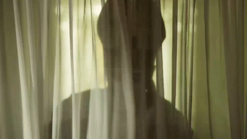 a man is in a curtained room looking outside