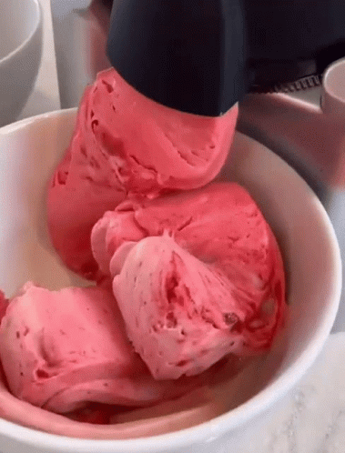a person holding a spoon in a bowl filled with ice cream