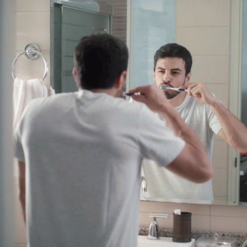 man brushing his teeth in front of a bathroom mirror