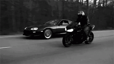 a man on a motorcycle with his helmet on, and the car behind him