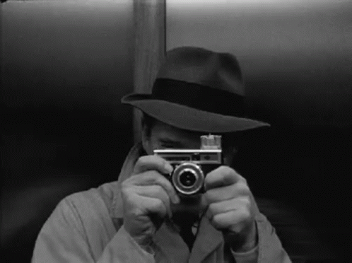 a man in a fedora taking a po with a camera