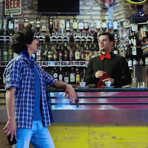 two people are talking in front of a bar