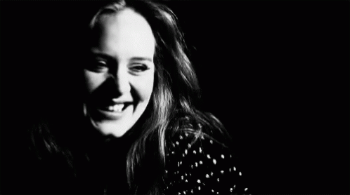 woman laughing while looking at camera, against black background