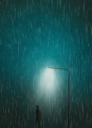a man stands under a street lamp on a rainy night