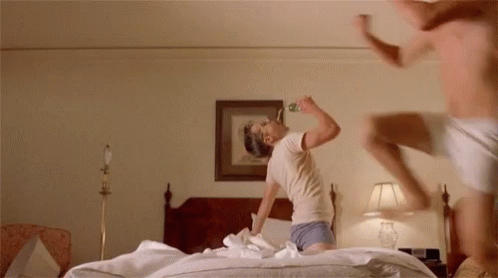 a person is jumping on the bed drinking beer