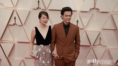 two people in front of an award with oscars backdrop