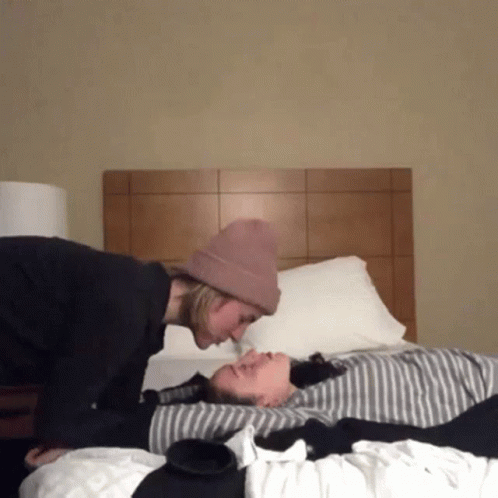 man holding another mans face as they sleep on a bed