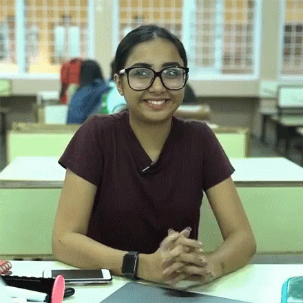 a person is sitting in a classroom wearing eye glasses