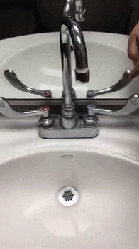 someone in blue gloves washing their hand on a white sink