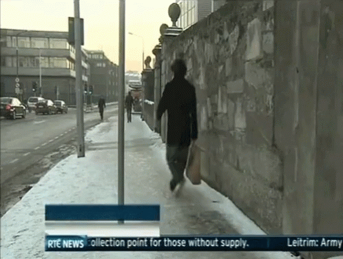 a tv screen showing a man walking down the sidewalk