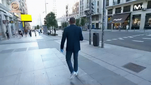 a man in a suit walking across a sidewalk