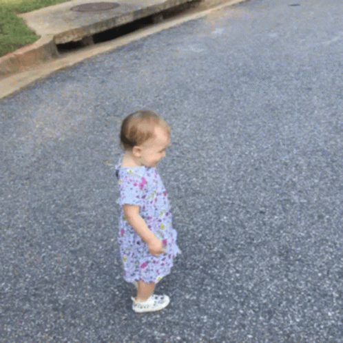 a small child walking down a street near a park