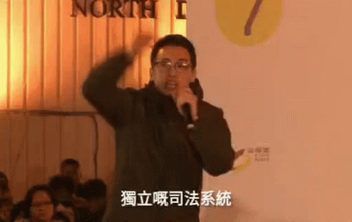 an asian man speaking on stage in front of a crowd