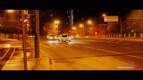 two cars driving down a street at night