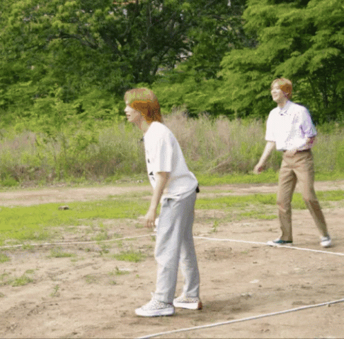 two people standing on dirt ground holding onto baseball bats