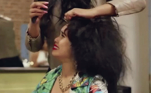 a woman who is using scissors to comb her long dark hair
