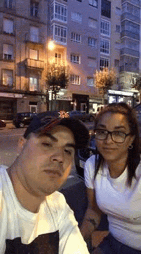 two people sit down on the street in front of a tall building