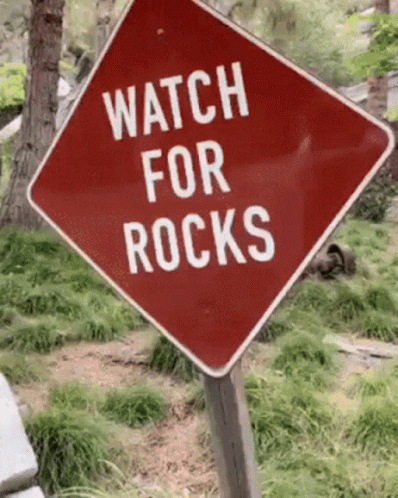 a sign that reads watch for rocks in front of trees